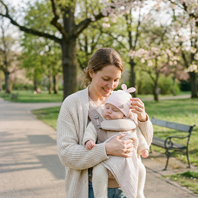 promenade au parc avec bébé qui porte son bonnet bébé naissance rose doux