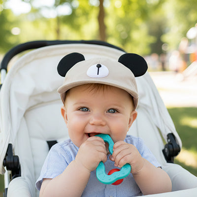 bébé joue avec anneau de detition et porte sa casquette bebe