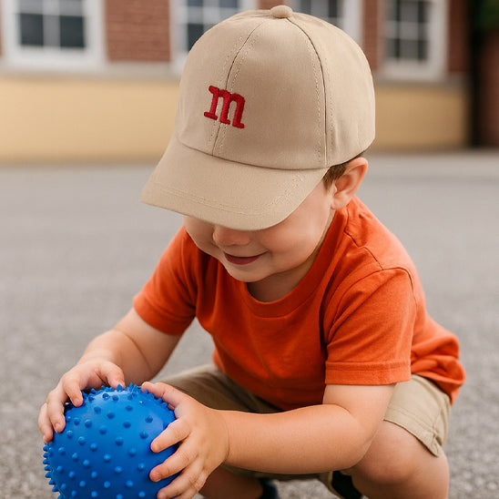 bébé porte sa casquette bebe beige avec la lettre M