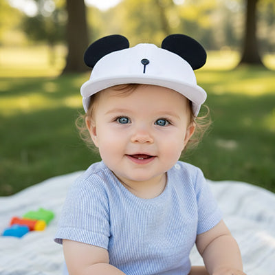 bébé assis au parc et porte sa casquette bebe