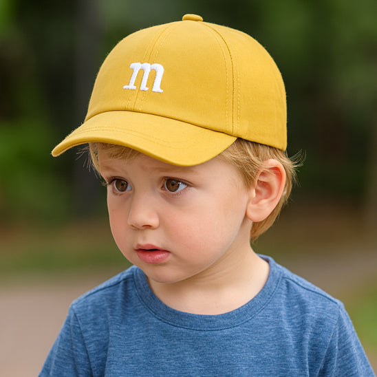 bébé porte sa casquette bebe jaune avec la lettre M