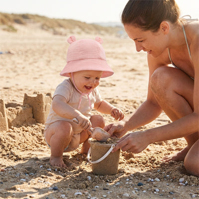 bébé à la plage avec maman protégé du soleil par son chapeau bébé