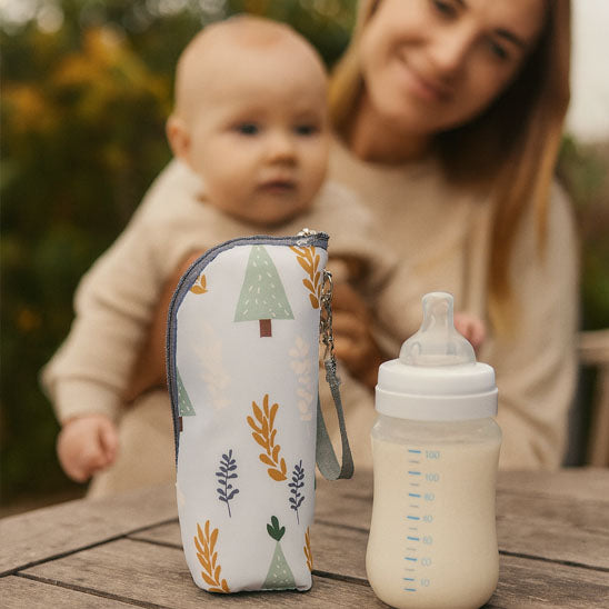 bébé regarde son biberon et son porte biberon