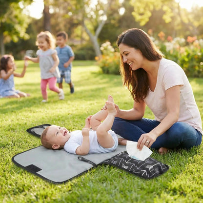 maman change bébé au parc sur son tapis pour changer bebe