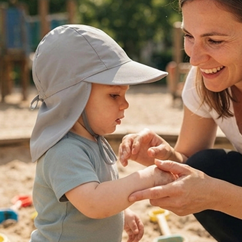 bébé joue au parc bien protégé du soleil par sa casquette bebe