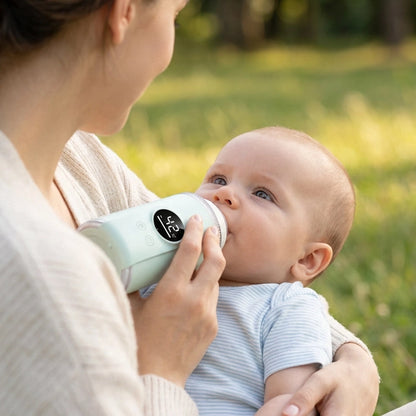 maman donne le biberon a bébé au parc grâce a son chauffe biberon nomade