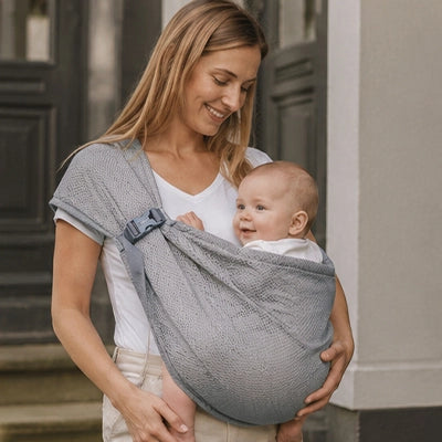 maman porte bébé dans son echarpe de portage et bébé sourit