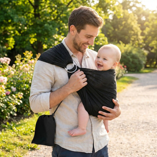 papa au parc porte son bébé dans son echarpe de portage sling