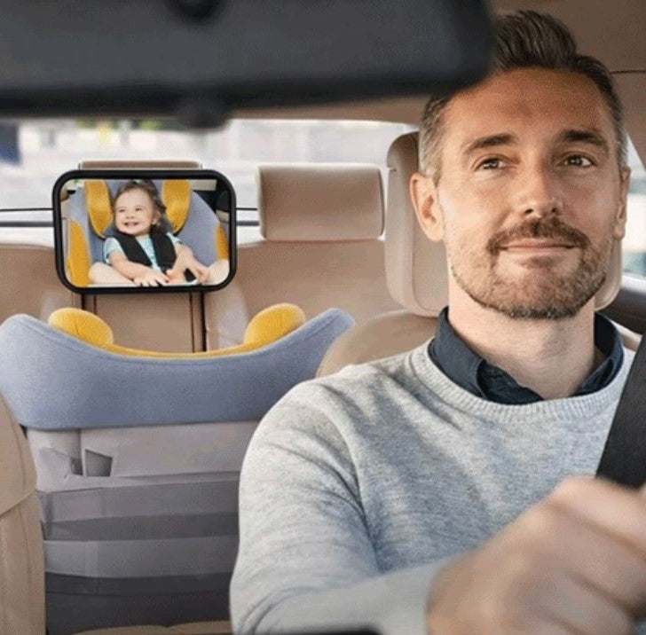 bébé installé dans son siège auto et regarde papa dans son miroir pour voiture bébé