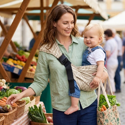 maman au marché avec bébé dans son porte bébé koala beige