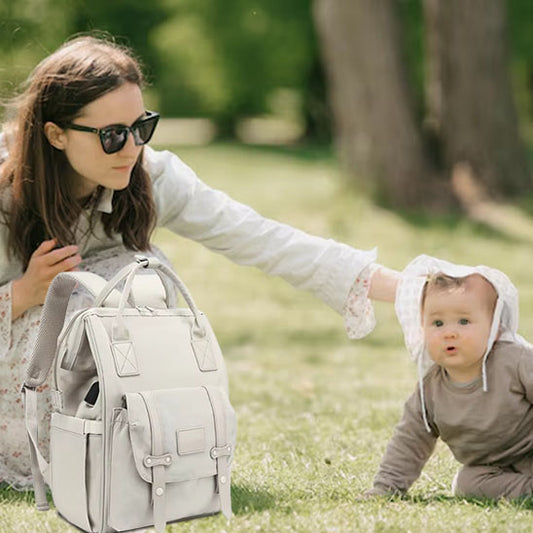 maman tient le sac à dos à langer et bébé joue