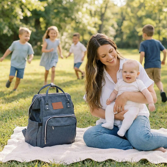 maman et bébé au parc à coté de leur sac à dos à langer