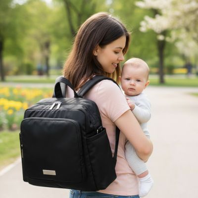 maman porte son bébé et son sac à dos à langer noir