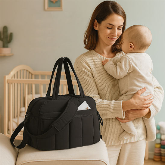 sac a langer bebe noir et bébé dans les bras de sa maman