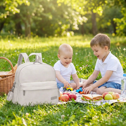les enfants jouent et le sac a langer beige posé sur le gazon