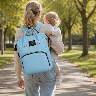 maman au parc avec bébé porte son sac a langer bleu ciel