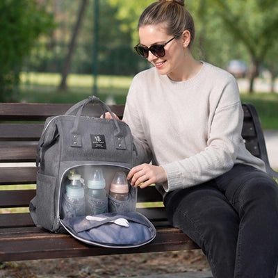 maman range les biberons dans le sac a langer gris au parc