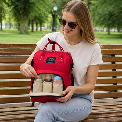 maman au parc sort le biberon de son sac a langer rouge