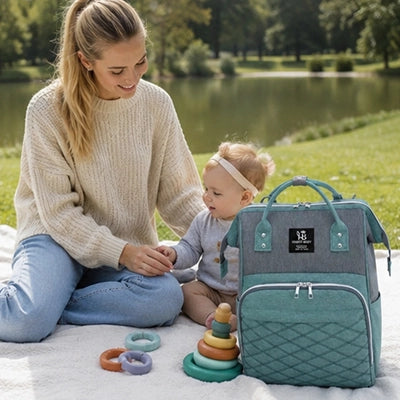 maman au parc avec bébé et e sac a langer posé à coté