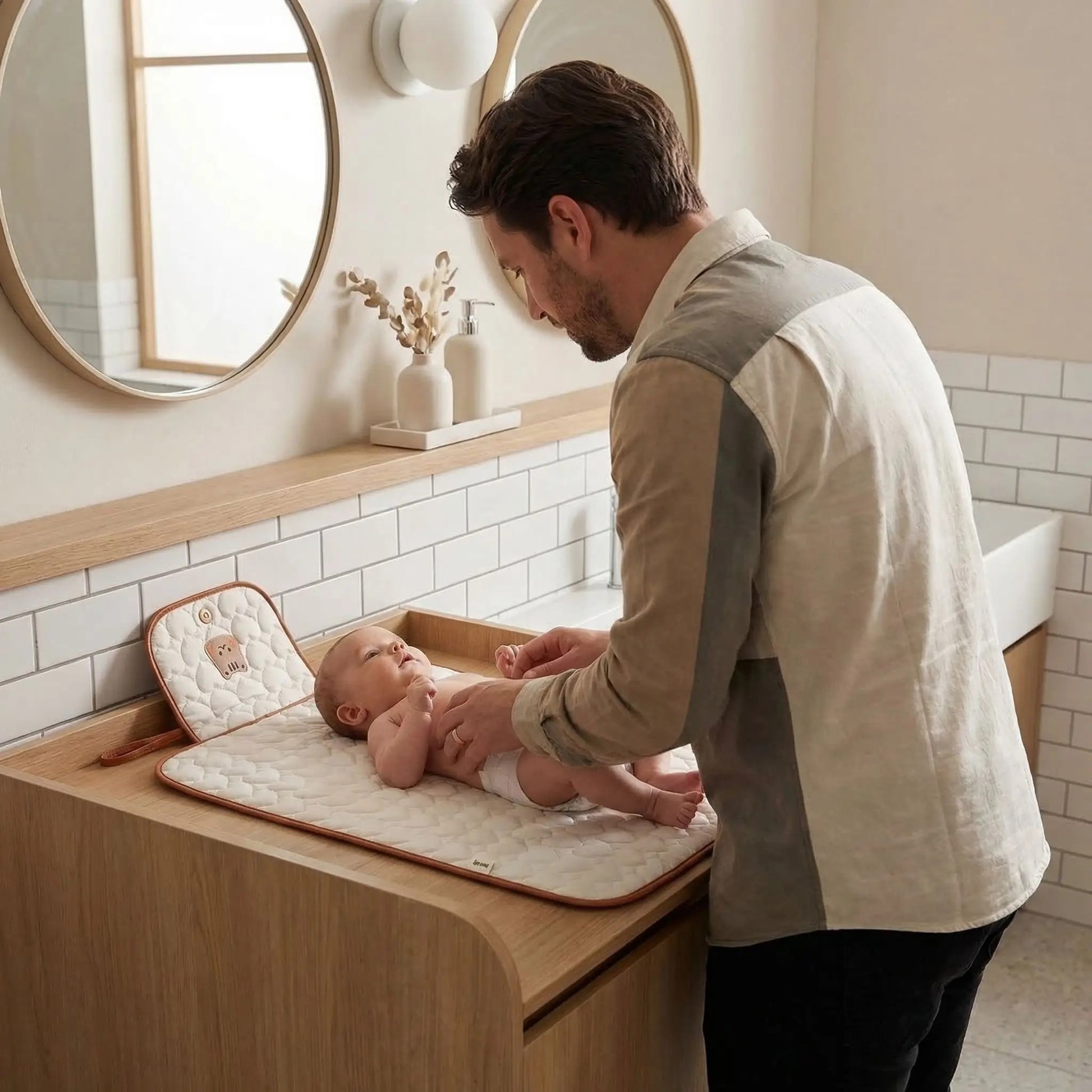 papa change bébé sur son tapis à langer nomade sur la table à langer les toilettes